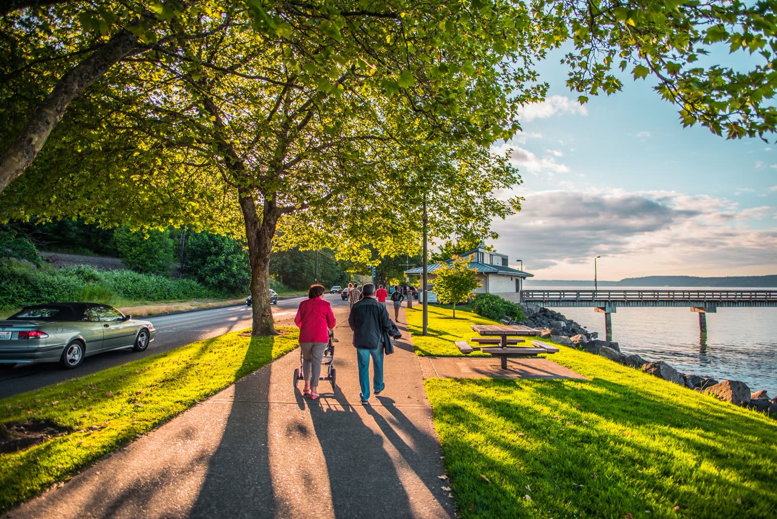 people in short sleeves walking a sunny southern riverside path / clear blue sky over dry grass and pine woods in early autumn / bright afternoon sun over a small southern downtown
