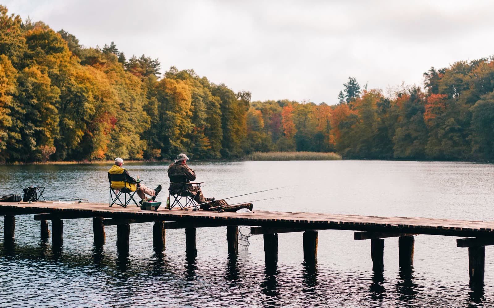 people fishing from a lakeside dock on a calm autumn afternoon / calm coastal water under a clear sky at sunset / wide open blue sky over a southern river town