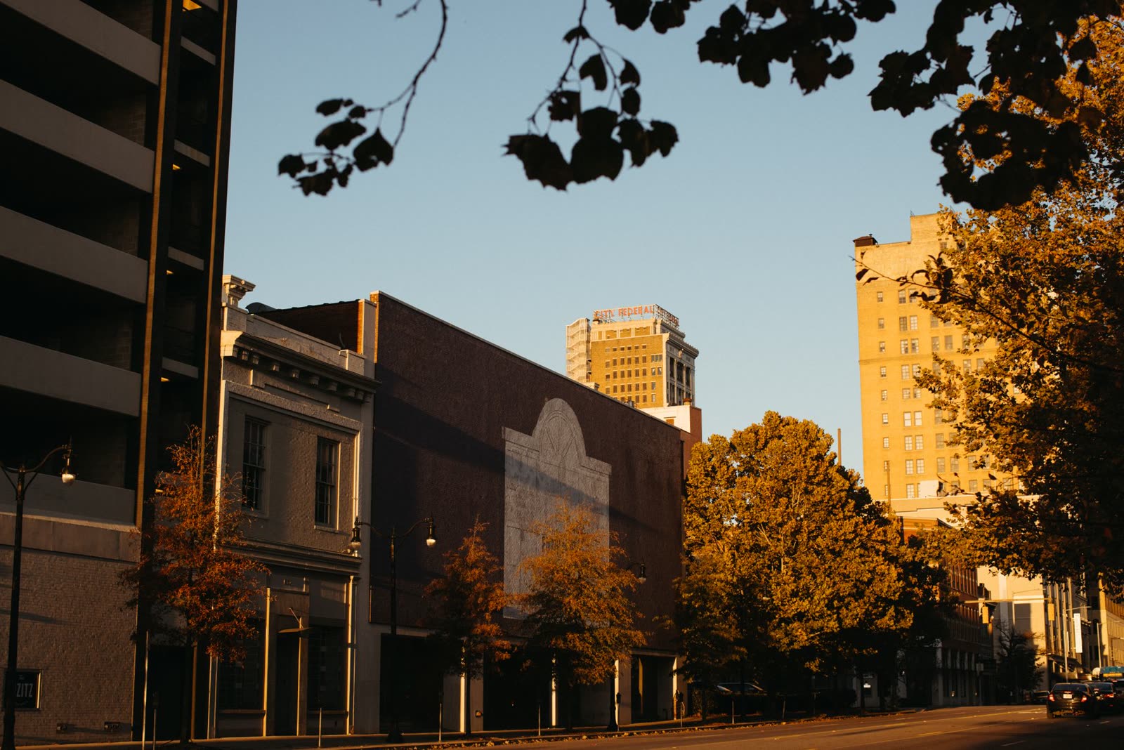 people walking a riverside trail on a warm sunny autumn afternoon / family on a porch with coffee on a clear fall morning / golden afternoon sunlight over a small Southern downtown in autumn