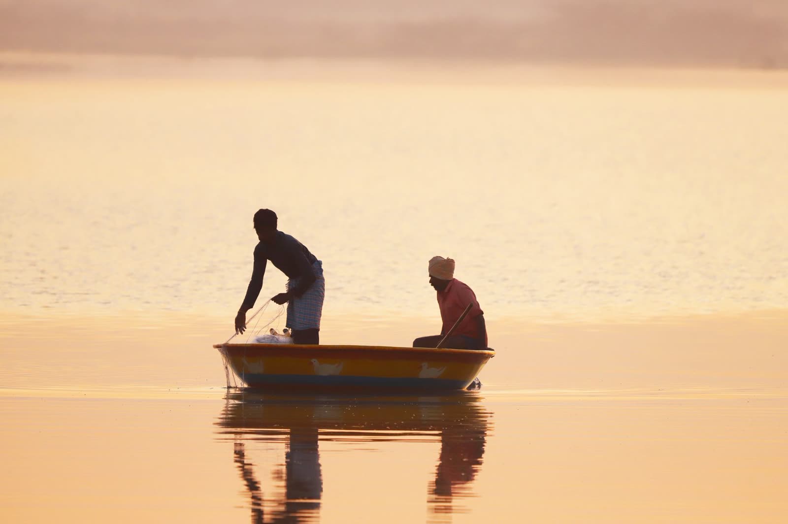 two anglers in a small boat on a calm lake at sunrise in early autumn / family sitting on a wooden lake dock on a sunny fall afternoon / glassy lake water reflecting a clear morning sky