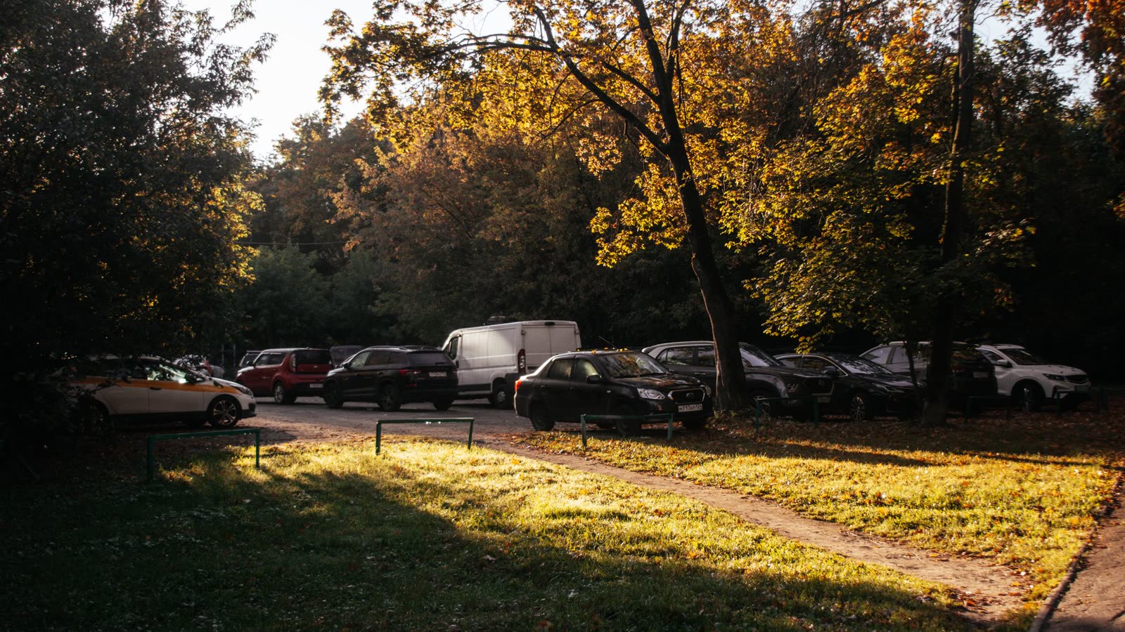 people in short sleeves walking a riverside trail on a warm autumn afternoon / warm sunny afternoon in a small southern downtown in late fall / dry fallen leaves and pine straw in bright autumn sunlight