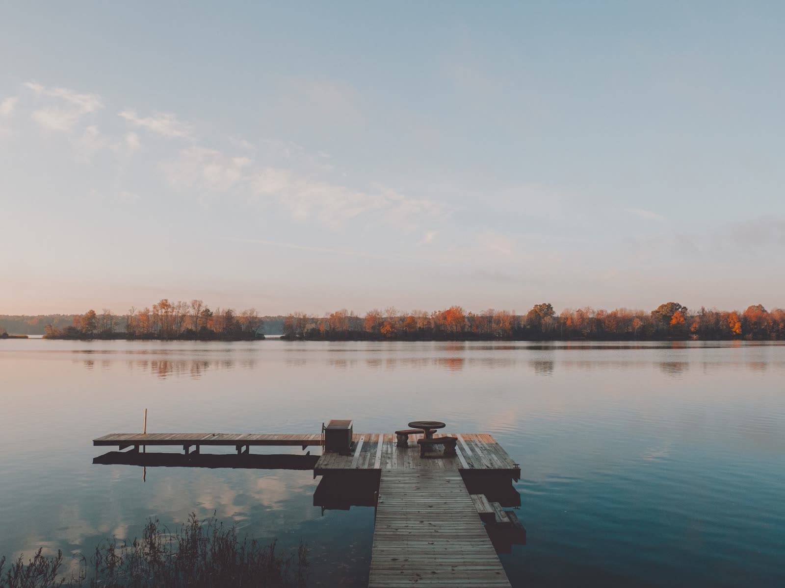 anglers in a small boat on a calm lake at sunrise in autumn / wooden dock over still lake water on a cool fall morning / rain clouds building over a southern reservoir in the afternoon